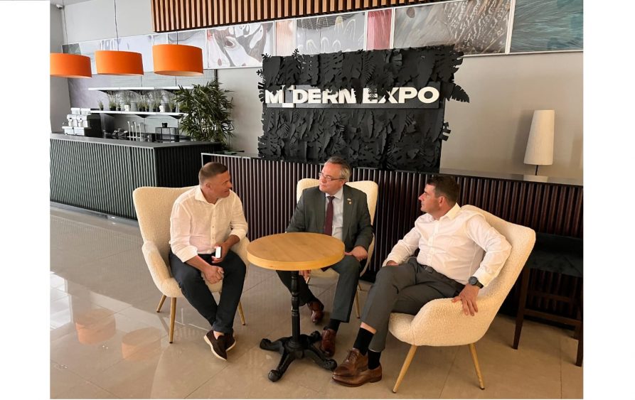 Wicemarszałek Zbigniew Wojciechowski w towarzystwie dwóch męzczyzn siedzą na fotelach przy okrągłym stoliku