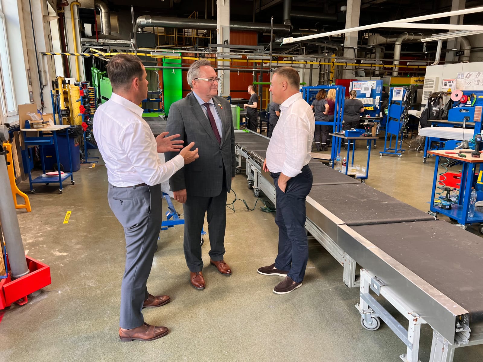Wicemarszałek Zbigniew Wojciechowski w towarzystwie dwóch mężczyzn przechadza się po hali w fabryce