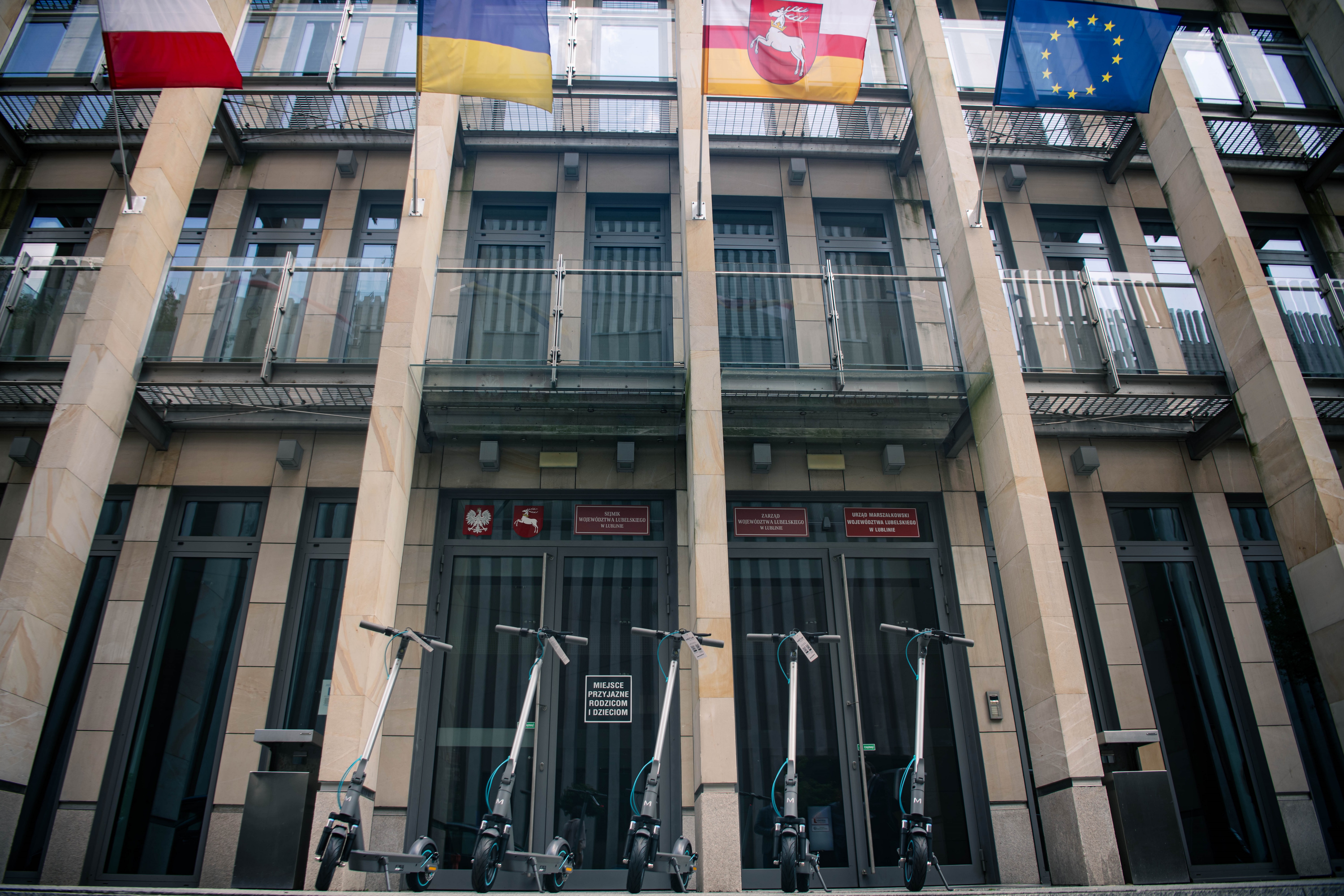 Kilka hulajnóg ustawionych przed wejściem do urzędu