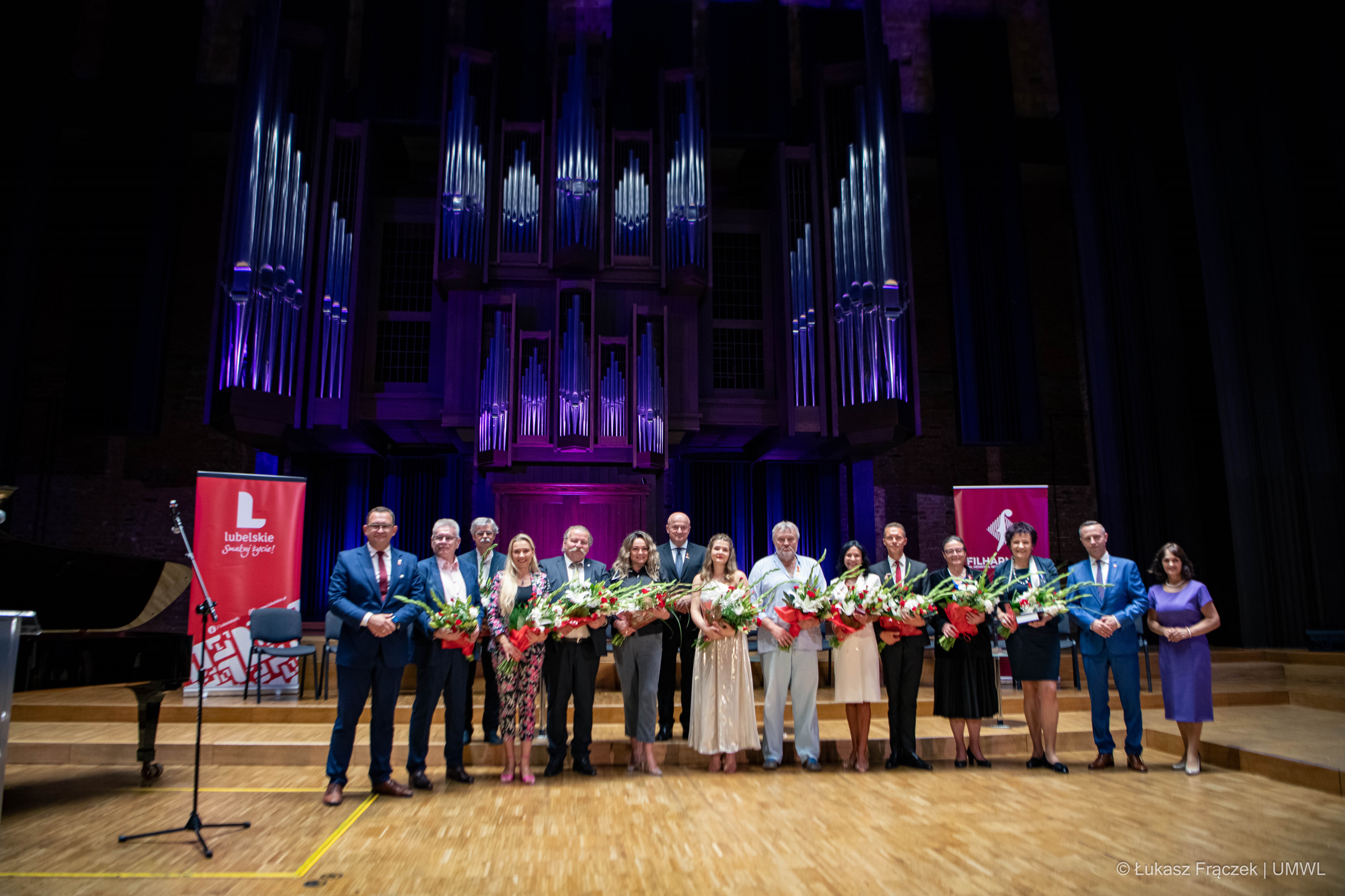 Na zdjęciu znajduje się kilkanaście osób, ustawionych na scenie, są to wszyscy laureaci wyróżnień w towarzystwie członków zarządu wl