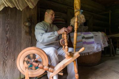 mężczyzna w lnianym stroju przy wrzecionie