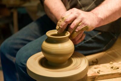 warsztat garncarski, męska dłoń lepiąca garnek z gliny