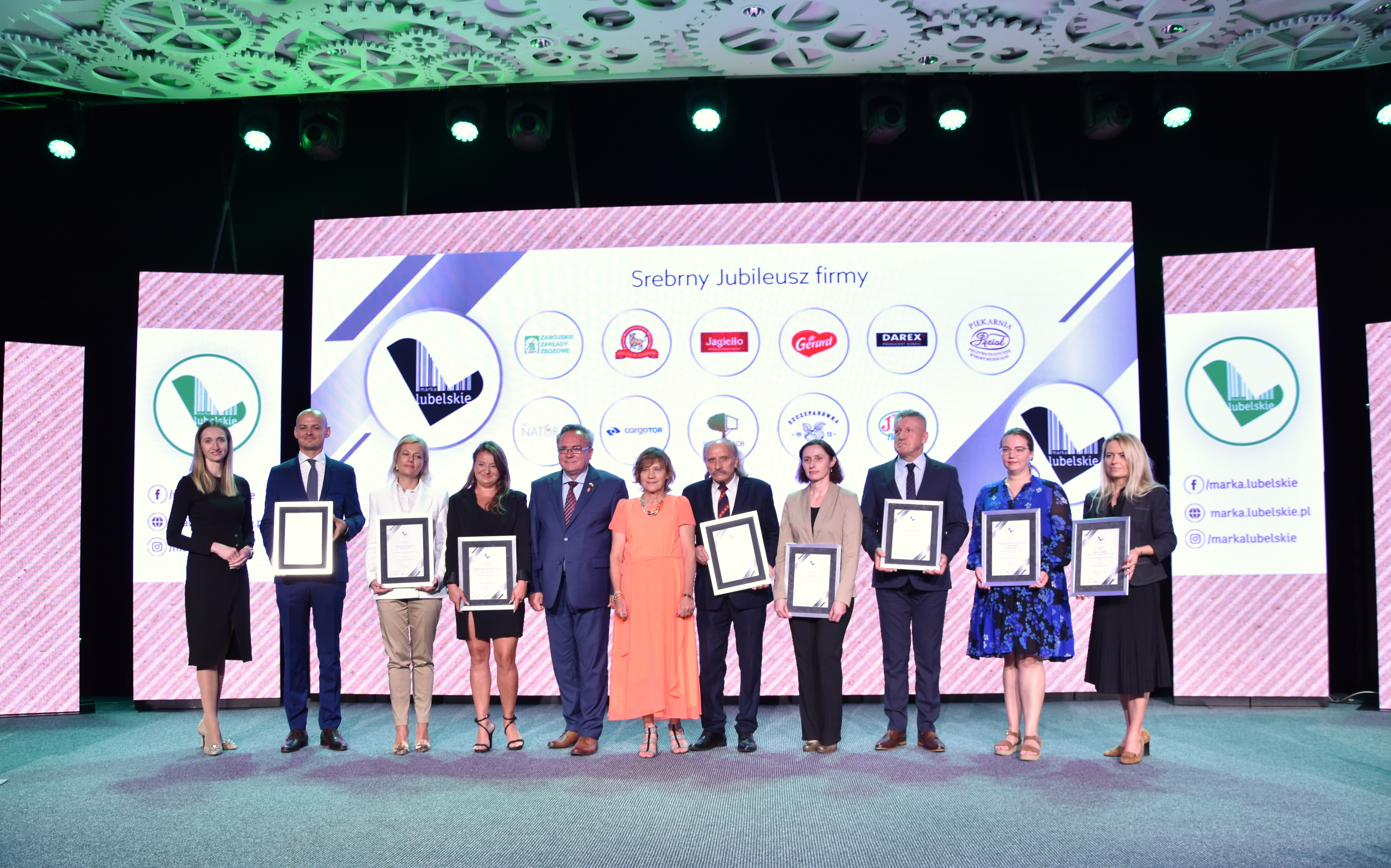 Zdjęcie zbiorowe laureatów statuetek, około dziesięciu osób stoi na scenie w towarzystwie wicemarszałka Zbigniewa Wojciechowskiego