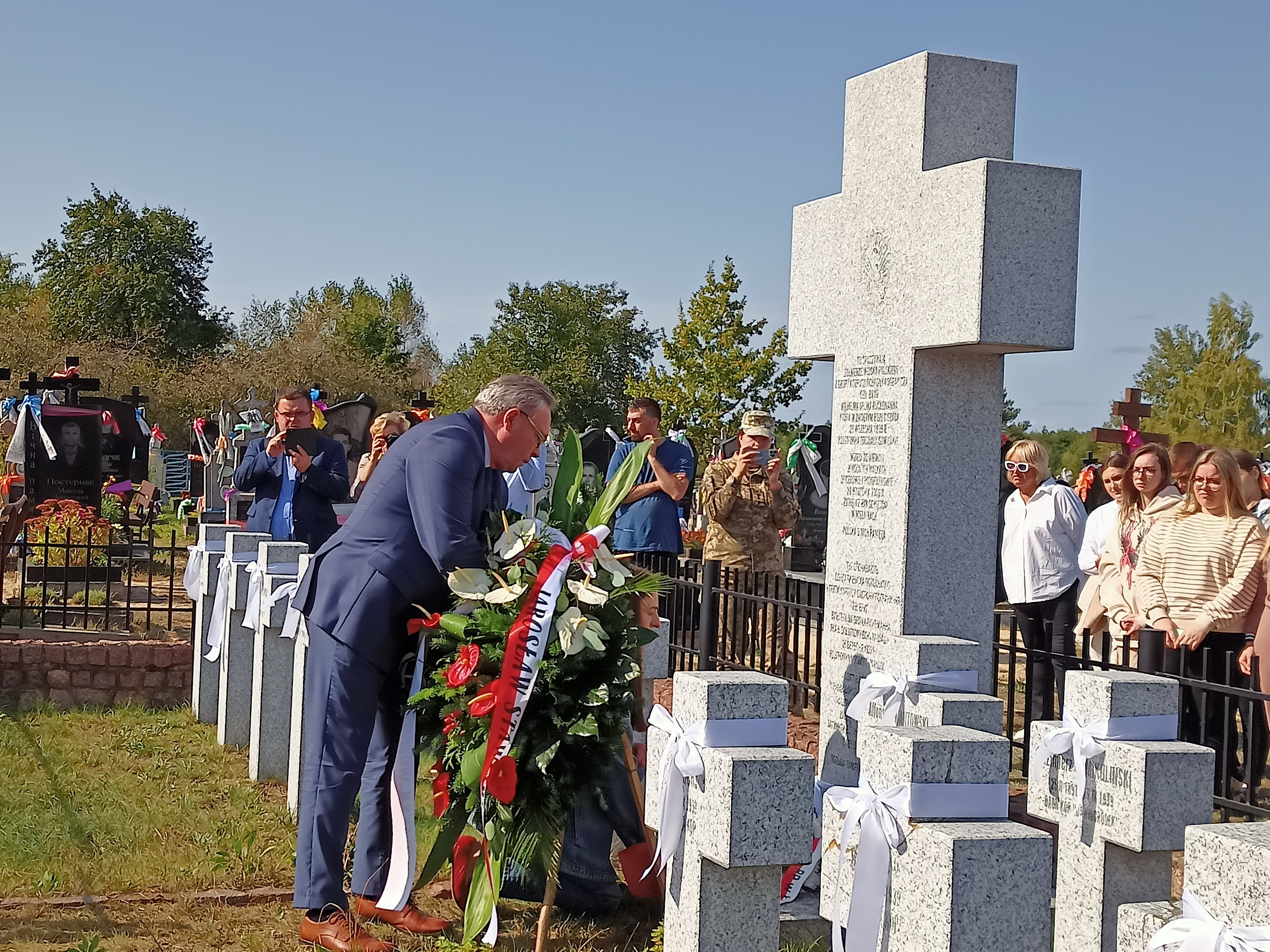Mężczyzna składający kwiaty na grobach na cmentarzu
