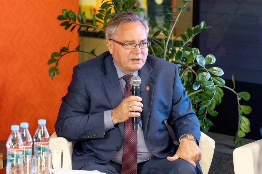 wicemarszałek Zbigniew Wojciechowski siedzi w fotelu w sali prasowej i udziela wypowiedzi do mikrofonu