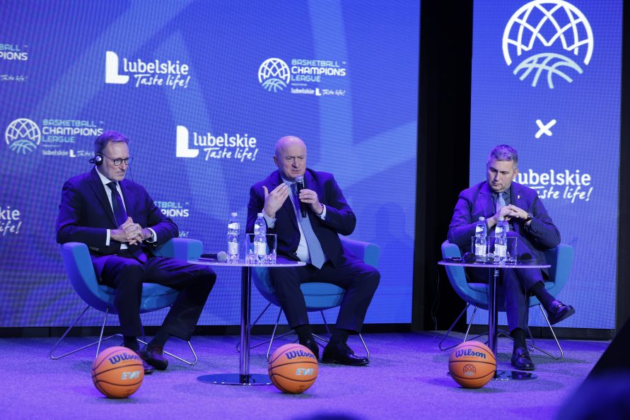 Marszałek Jarosław Stawiarski w towarzystwie dwóch mężczyzn. Siedzą na krzesłach na scenie podczas konferencji, przed nimi na scenie lezą trzy piłki do koszykówki