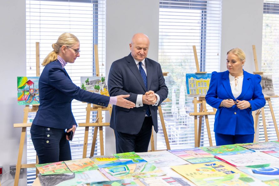 Marszałek Województwa Lubelskiego w towarzystwie dwóch dyrektorek przegląda prace konkursowe ułożone na stole