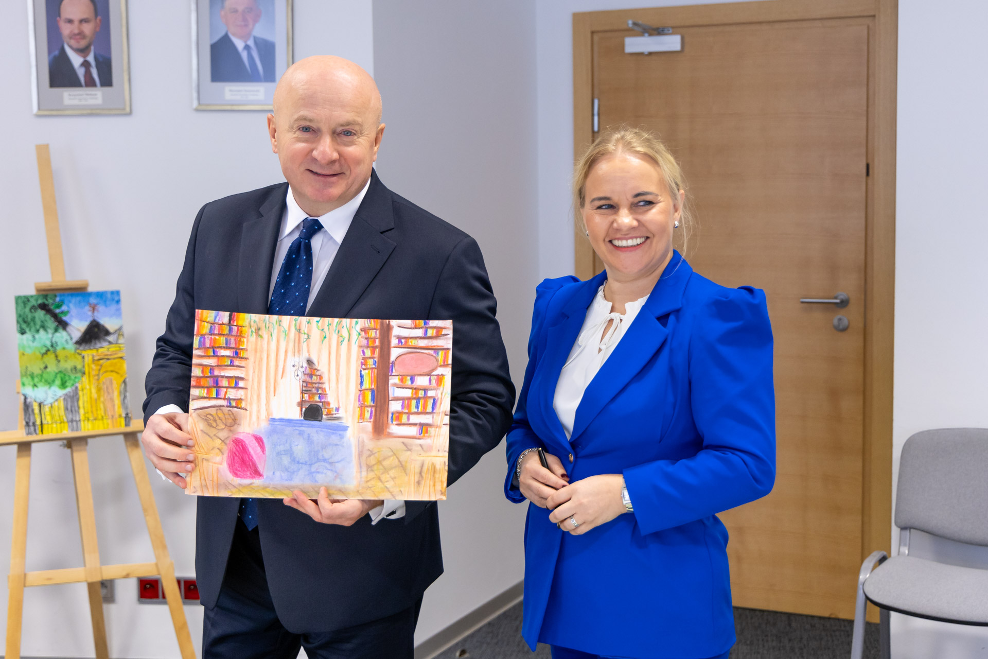 Marszałek Województwa Lubelskiego w towarzystwie dyrektorki RPO prezentuje jedną z konkursowych prac plastycznych