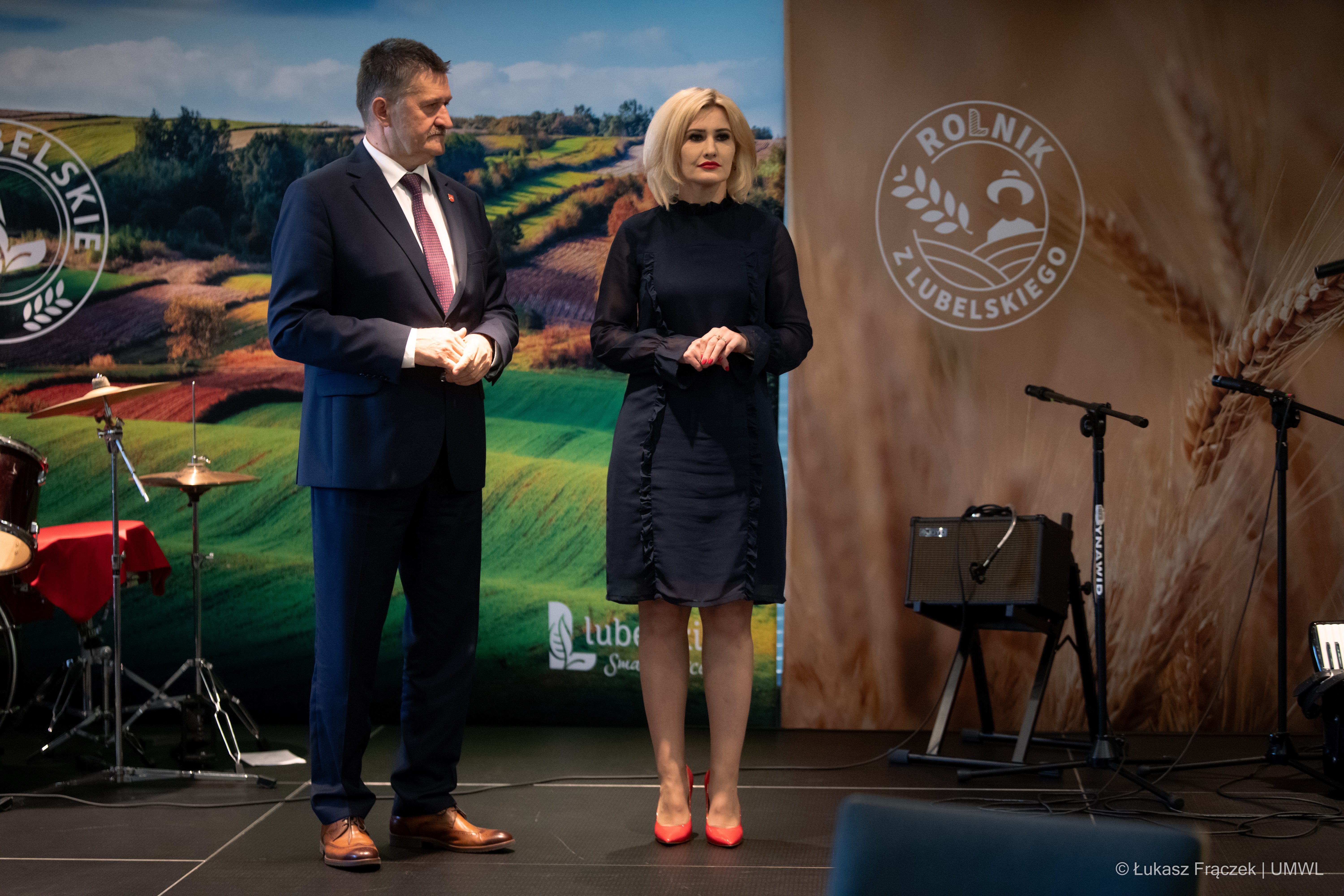 Zdzisław Szwed i Ewa Szałachwiej stoją na scenie , za nimi znajdują się ekrany wyświetalające grafiki promujące oba konkursy