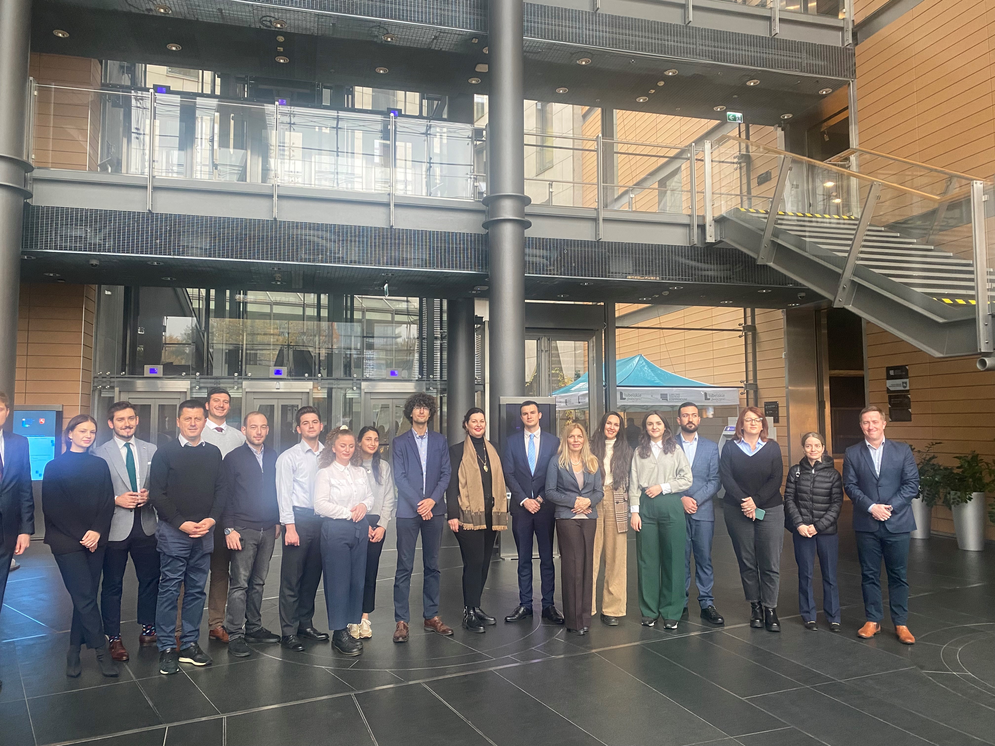 Grupa ludzi stoi w holu budynku.