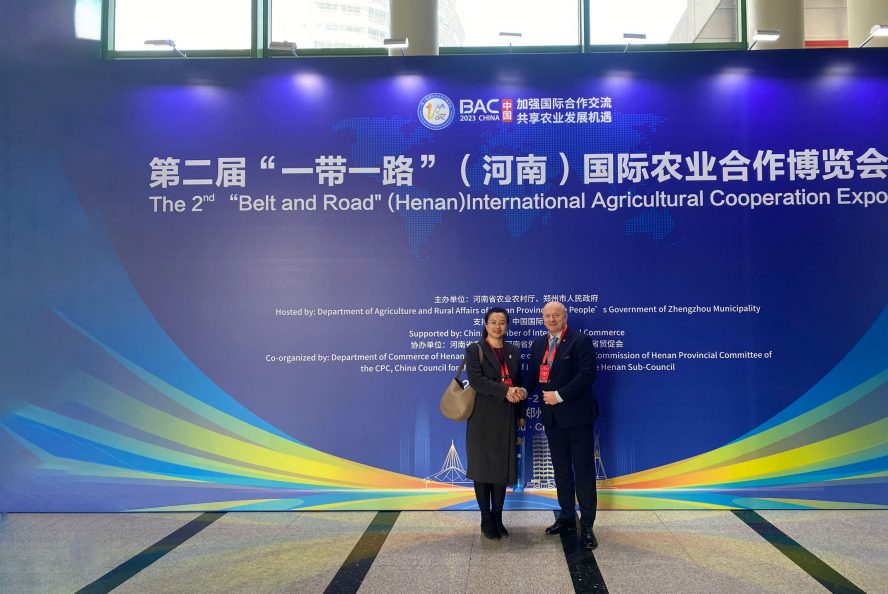 Marszałek Jarosław Stawiarski stoi na ściance z napisami w języku chińskim, towarzyszy mu kobieta