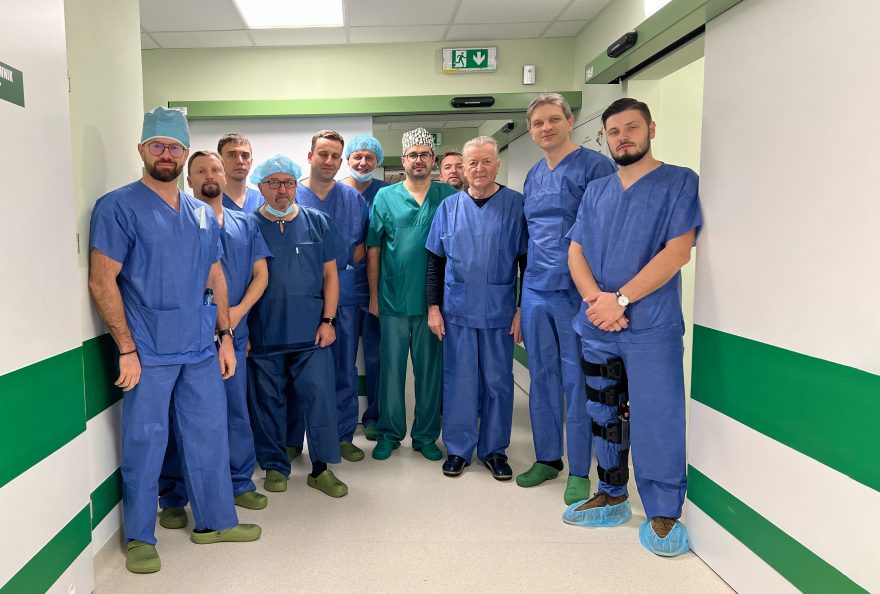 Około dziesięciu mężczyzn lekarzy chirurgów stoi w kitlach na korytarzu szpitala