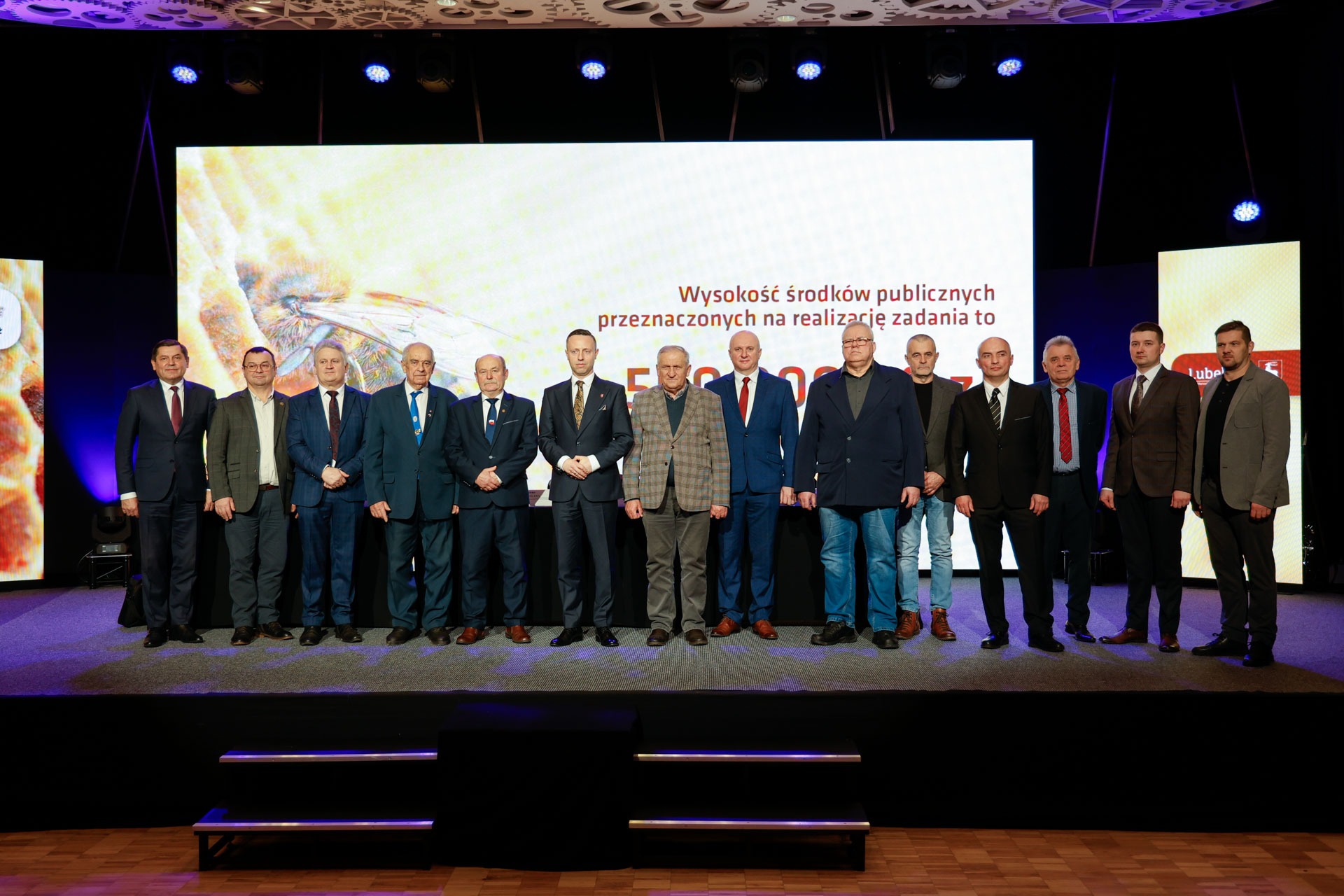 Wicemarszałek Michał Mulawa w towarzystwie wszystkich prelegentów obecnyh podczas konferencji. łącznie około dwunastu mężczyzn stojących na scenie i pozujących do zdjęcia