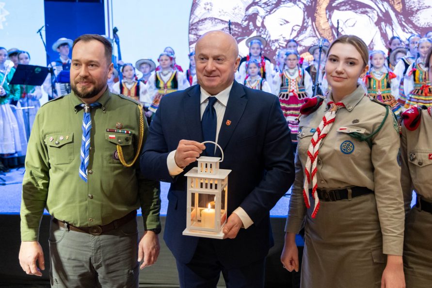 Marszałek Jarosław Stawiarski trzyma światełko pokoju, obok niego stoi dwóje harcerzy