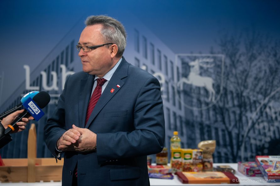 Wicemarszałek Zbigniew Wojciechowski uziela wypowiedzi do mikrofonu za nim w tle na stole widać artykuły spożywcze