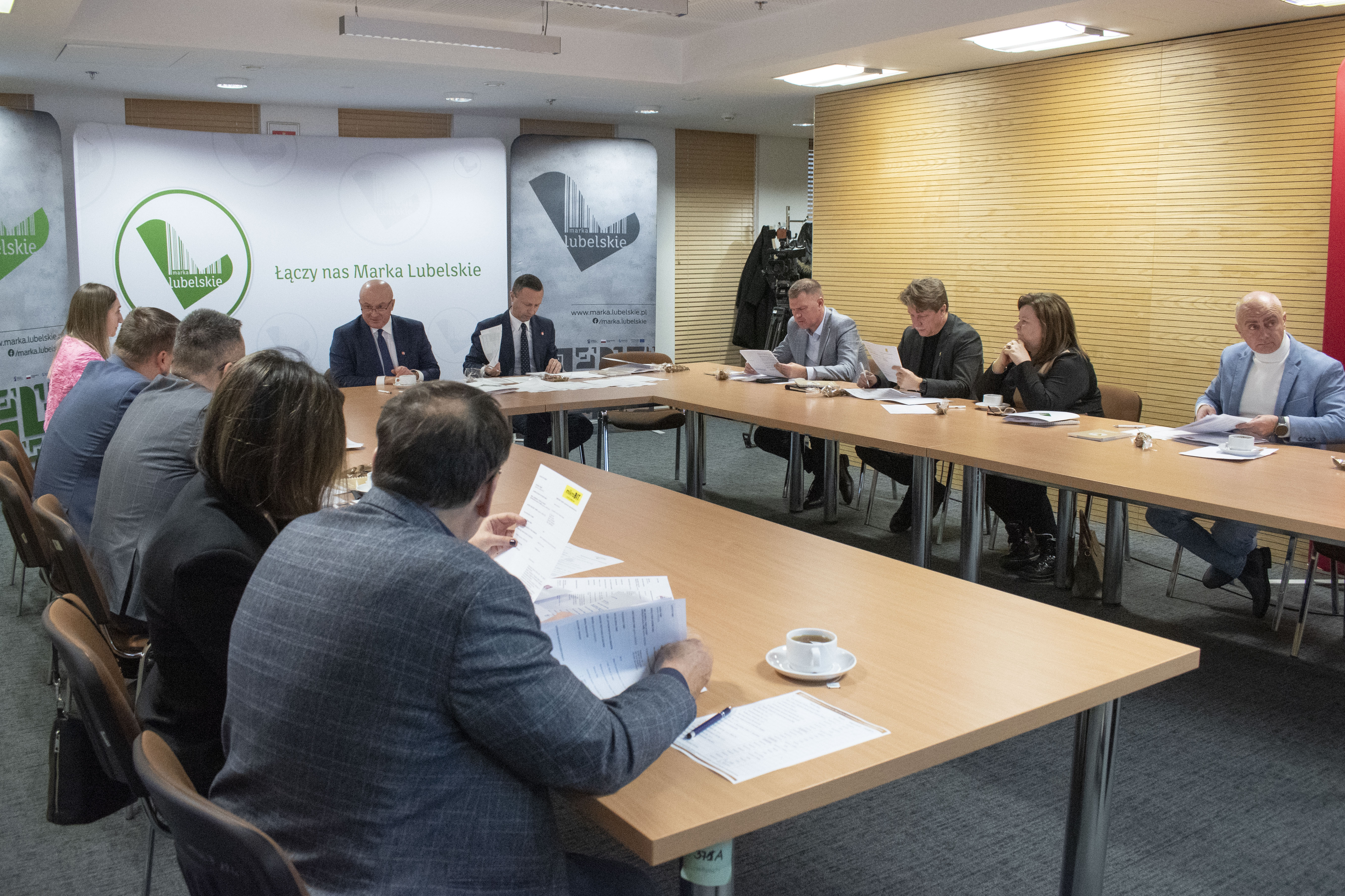 Widok na około dziesięć osób siedzących przy stołach ustawionych w podkowę