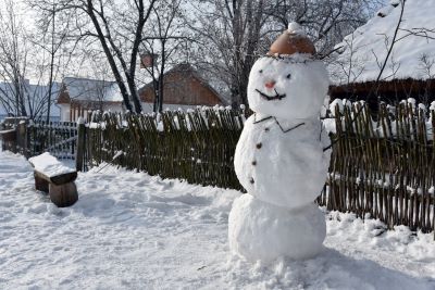 bałwan na tle płotu w oddali zabudowania skansenu
