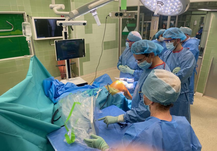 Trzech chirurgó stoi w sali operacyjnej podczas wykonywania zabiegu