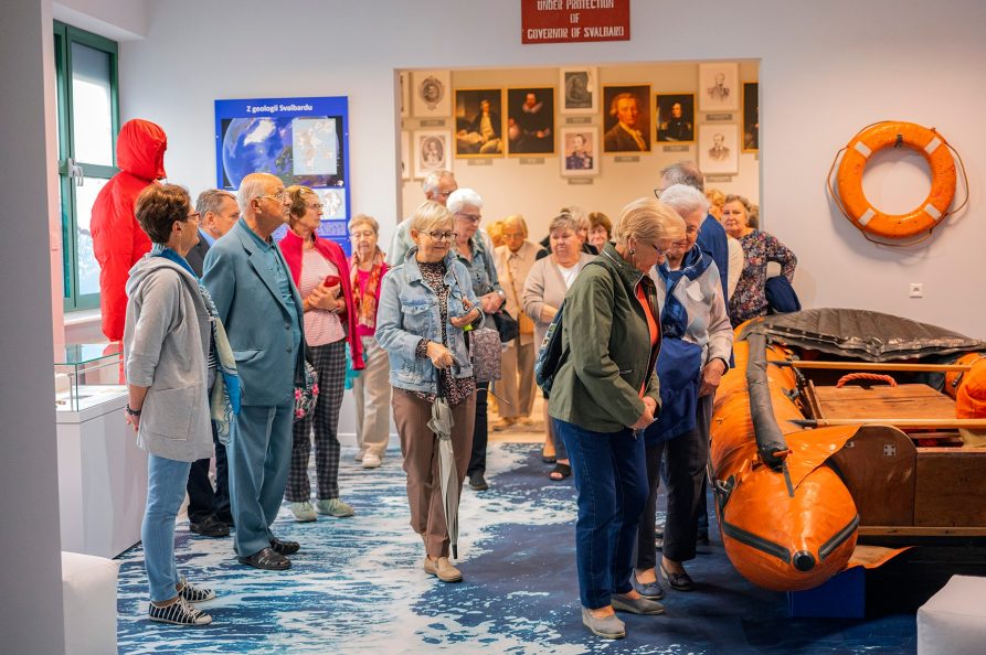 Około dziesięciu osób przechodzacych sie po wystawie w muzeum