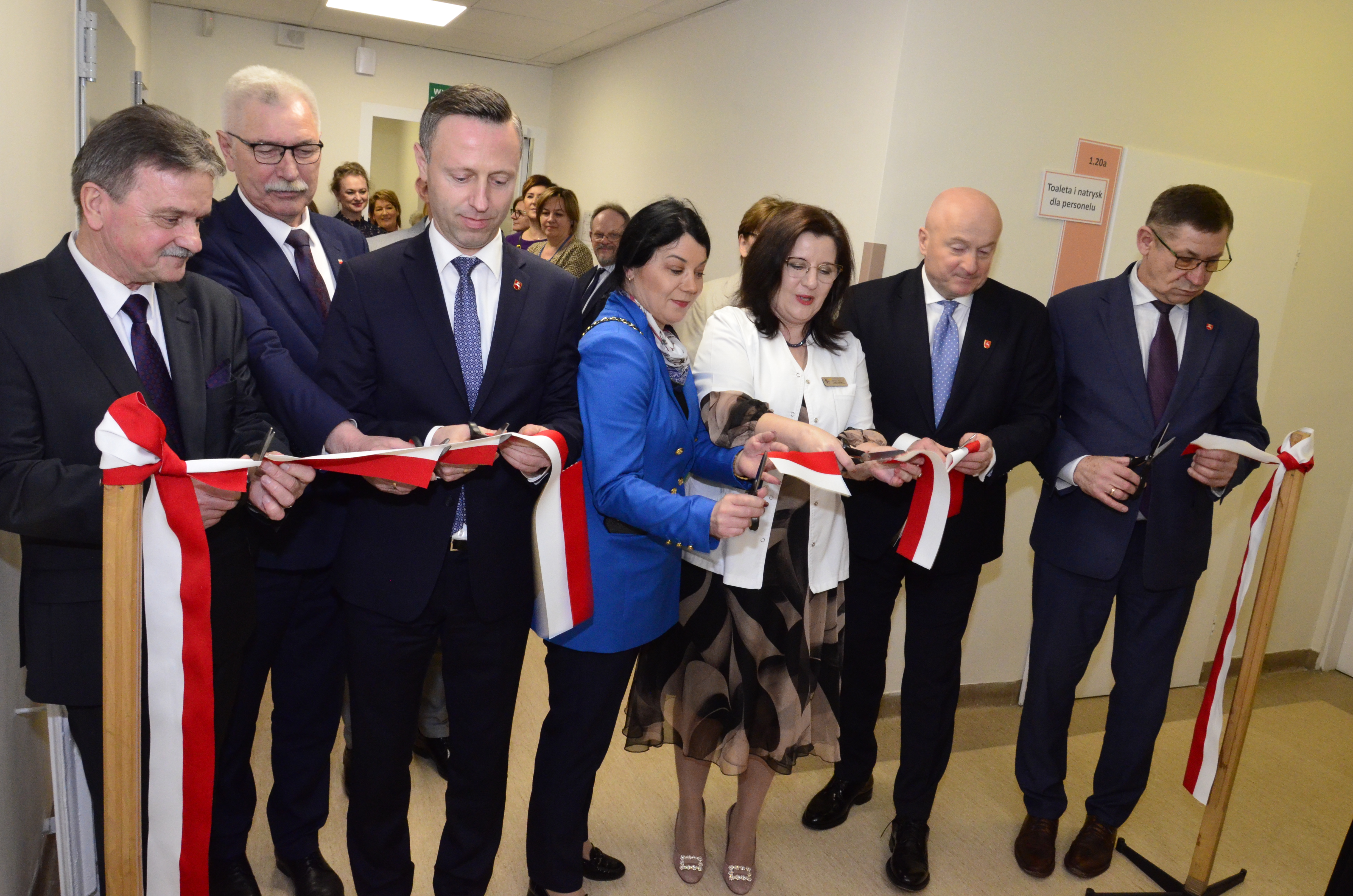 Kilkanascie osóbe w tym dwóch członków zarządu województwa lubelskiego stoi na korytarzu i przecina wstęgę podczas otwarcia obiektu