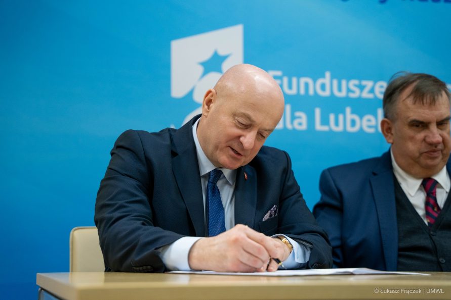 Marszałek Jarosław Stawiarski siedzi przy stole i podpisuje dokument