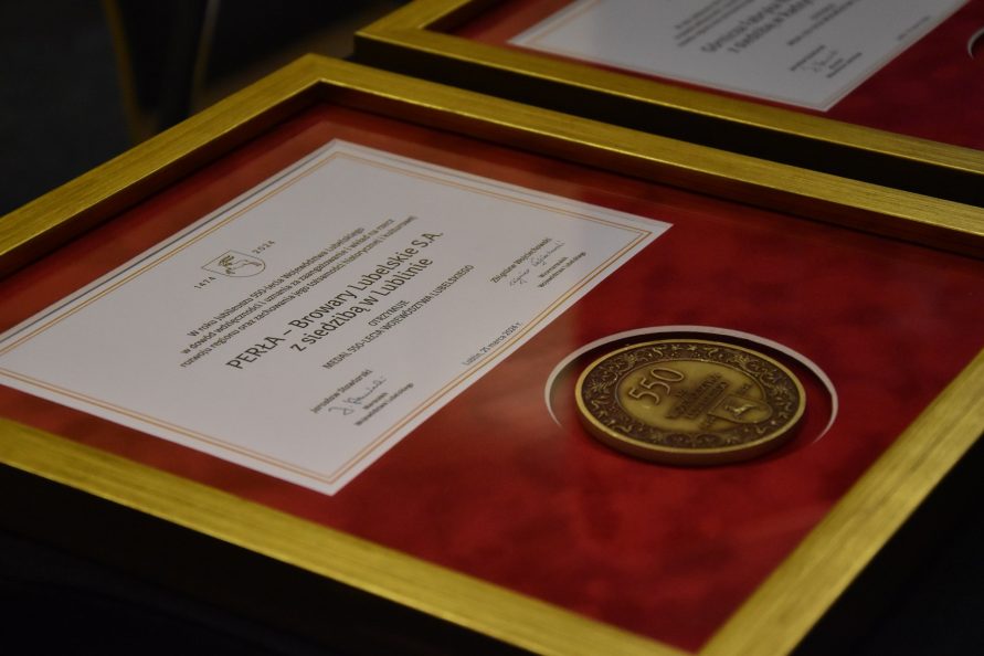 Medal wraz z dyplomem oprawiony w szklaną ramkę leży na stole