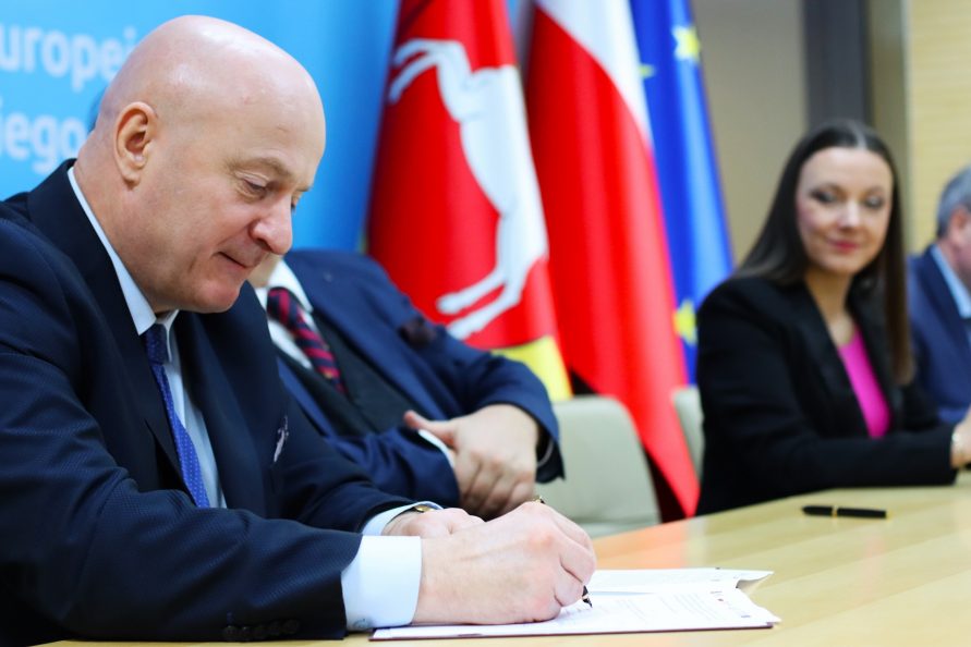 Marszałek Jarosław Stawiarski siedzi przy stole i podpisuje umowę o dodatkowe środki dla szpitala dziecięcego