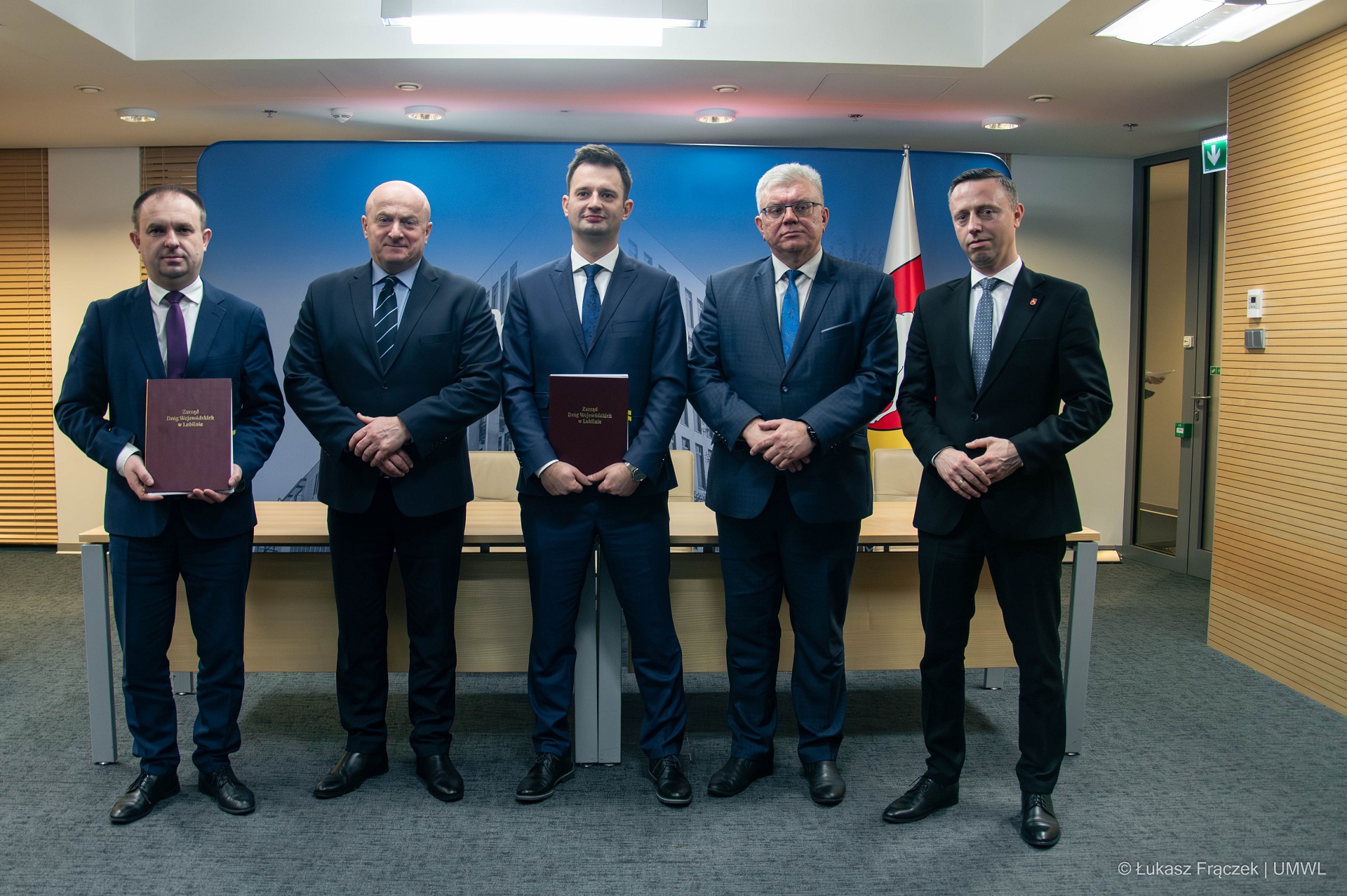 Przedstawiciele Zarzadu Województwa oraz Zarządu Dróg wojewódzkich i wykonawcy, łącznie jest to pięciu mężczyzn którzy stoja obok siebie i pozują do zdjęcia w sali konfernecyjnej