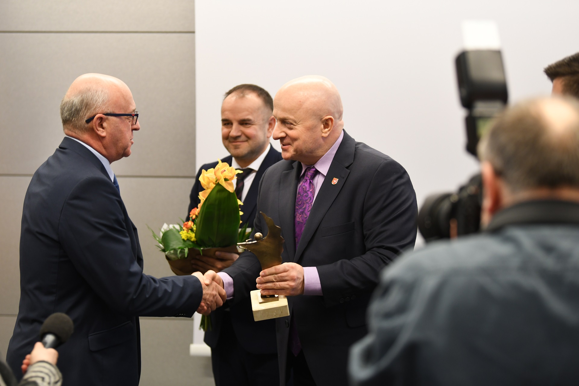 Marszałek Jarosław Stawiarski wręcza złotą statuetkę starszemu mężczyznie