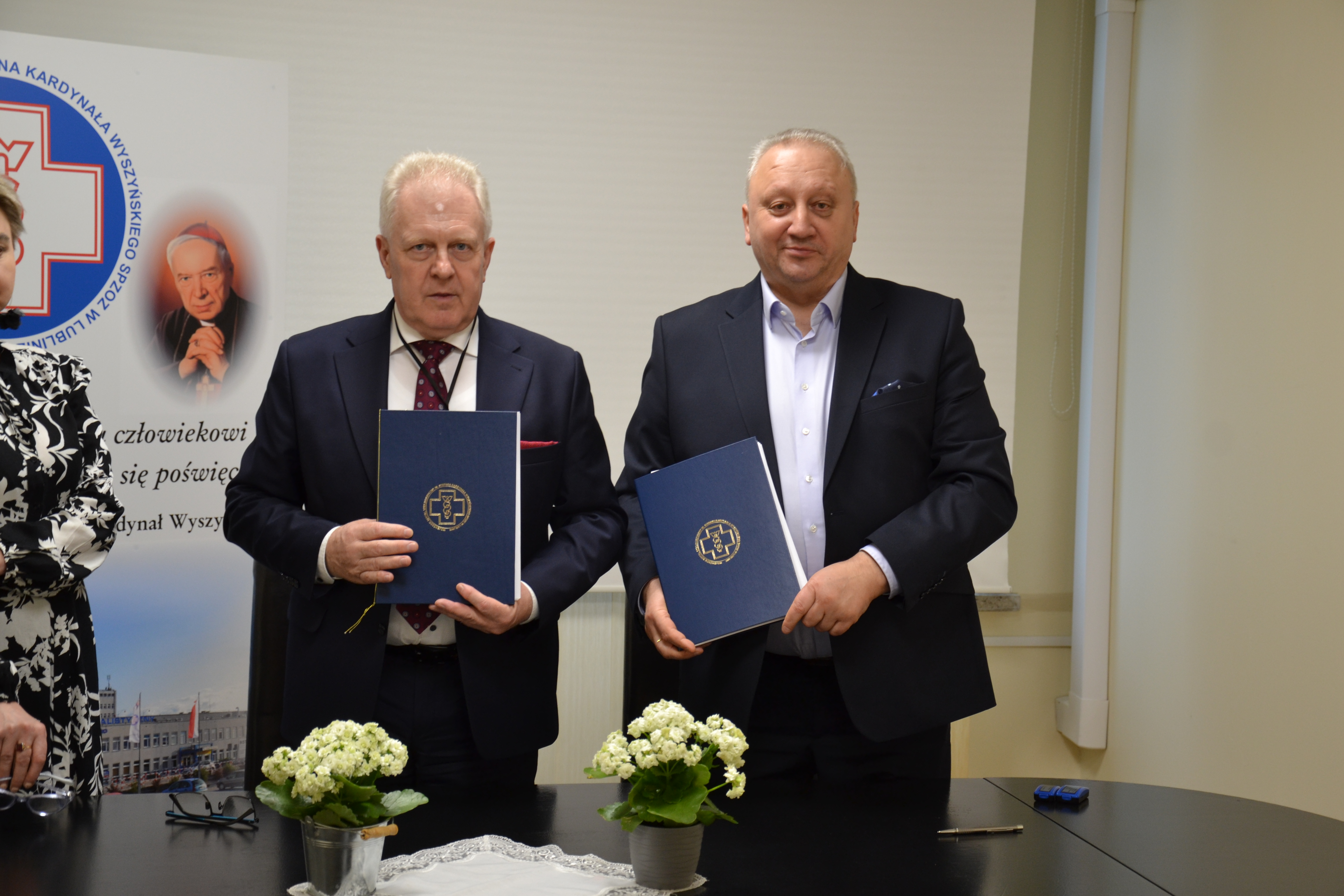 Dyrektor Szpitala na aLei Krasnickiec i przedstawiciel firmy MaxBud stoją wspólnie obok siebie i prezentują teczki z umowami