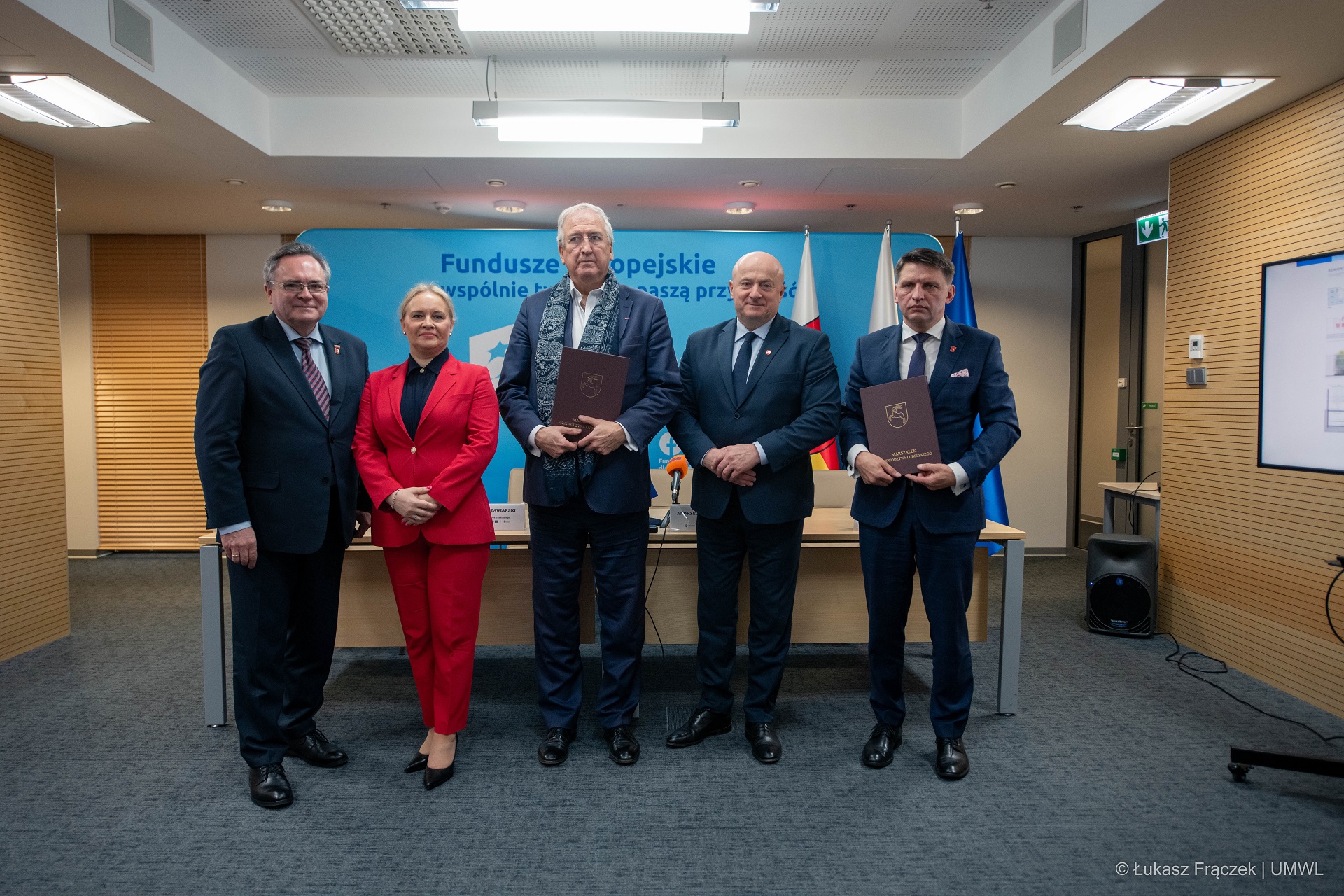 Czterech mężczyzn i jedna kobieta pozują do zdjęcia. Są to przedstawiciele władz samorządowych, urzędu marszałkowskiego i architekt, który przygotowuje projekt budynku teatru