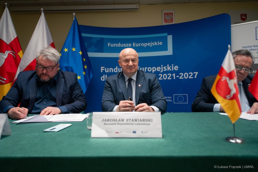 Marszałek Jarosław Stawiarski siedzi przy stole w towarzystwie wicemarszałka i dyrektora szpitala