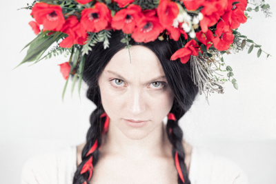 kobieta z warkoczami i wieńcu z czerwonych kwiatów