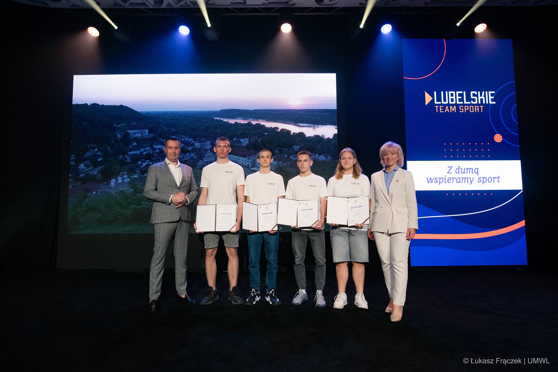 Czloenk Zarzadu Marcin Szewczak, Dyrektorka Departamnetu Promocji Sportu i Turystki UMWL oraz czwórka młodziezy pozują wspólnie do zdjęcia