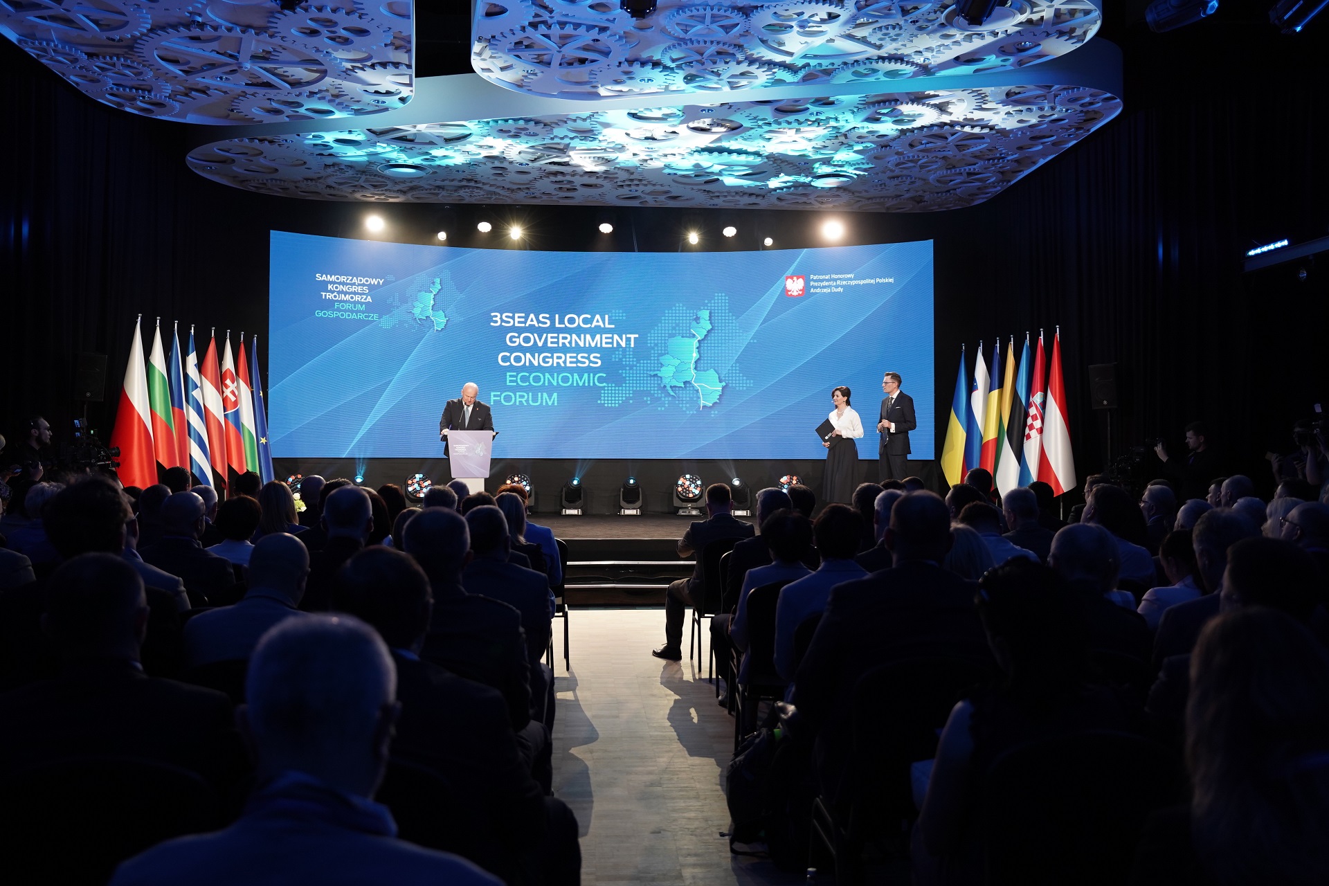 Duża sala konferencyjna z widokiem na scenę na które stoi marszałek województwa lubelskiego oraz dwoje konferansjerów