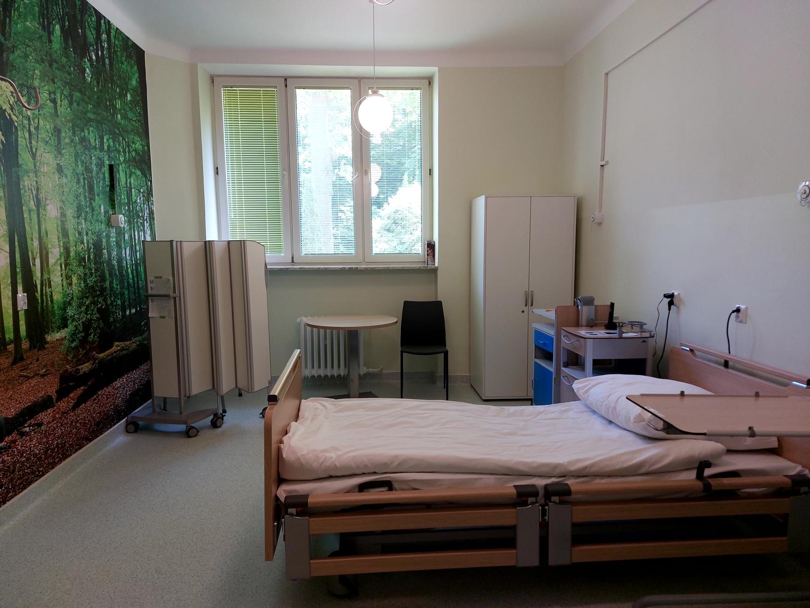 Widok na salę szpitalną z jednym pustym łóżkiem.