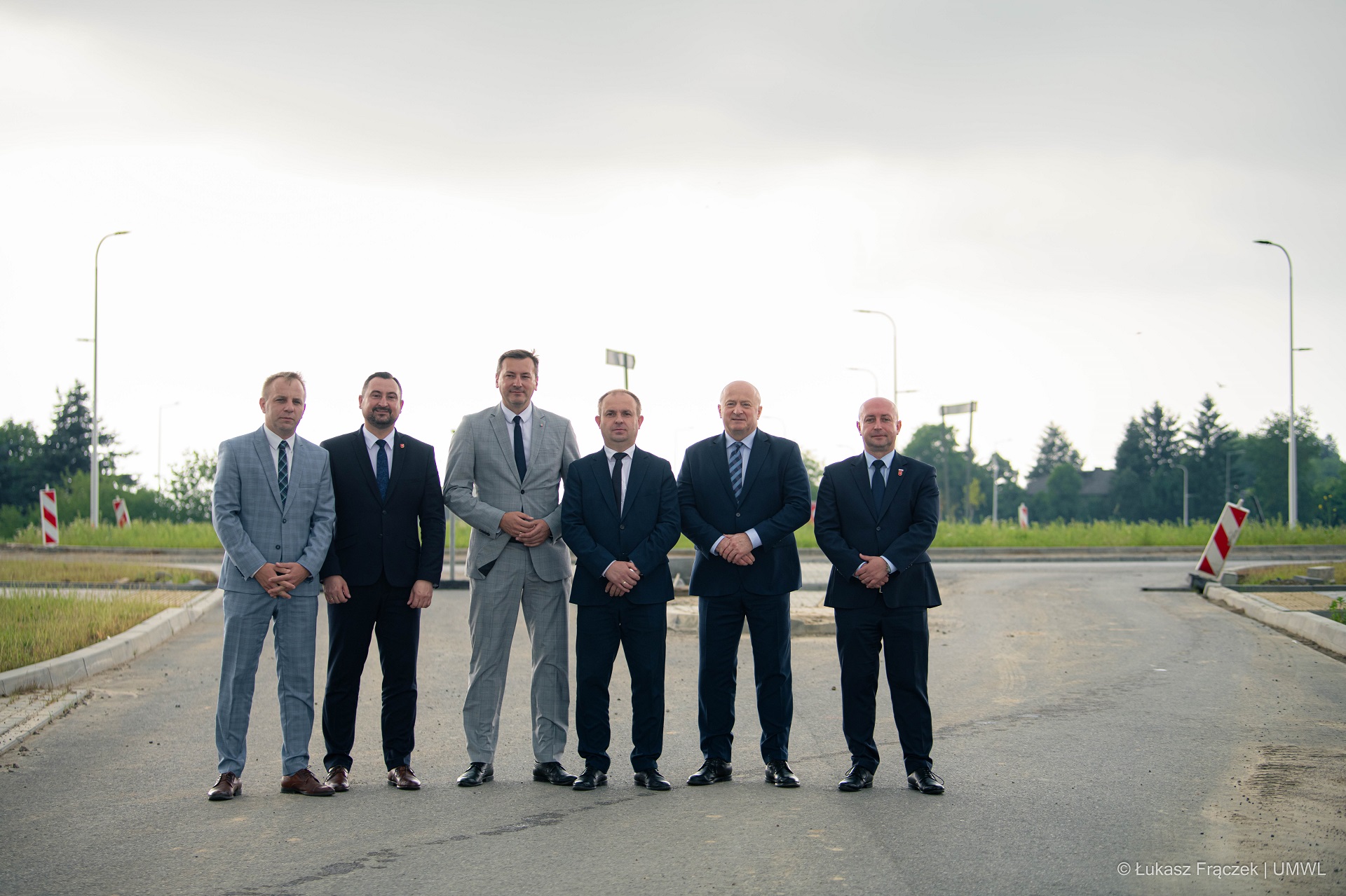 Sześciu mężczyszn stoi na drodze asfaltowej, nowobudowanej obowodnicy, są to przedstawiciele zarządu województwa lubelskiego i firmy Strabag budującej drogę