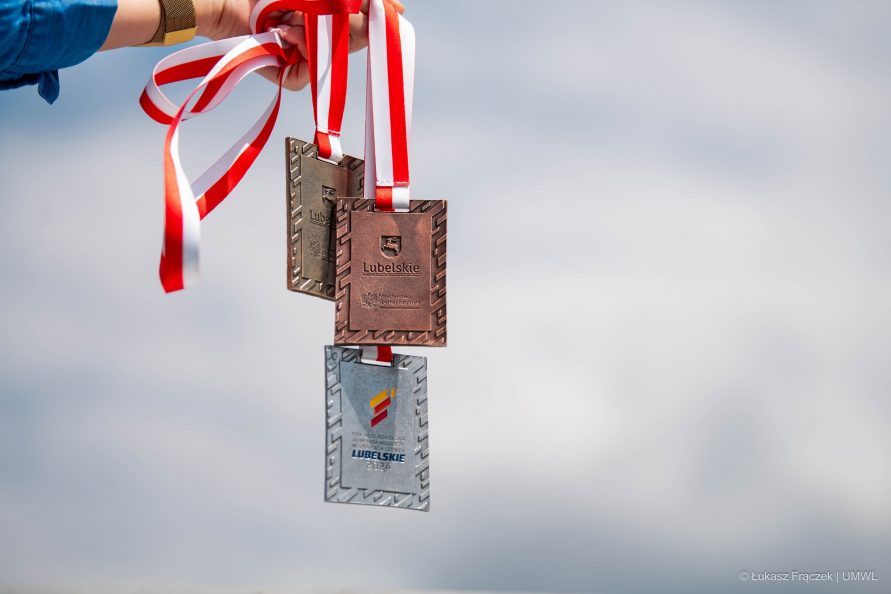 Wyciągnięta ręka, która trzyma trzy medale