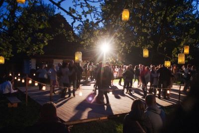 Ludzie tańczący nocą na drewnianym podeście ustawionym na dworze