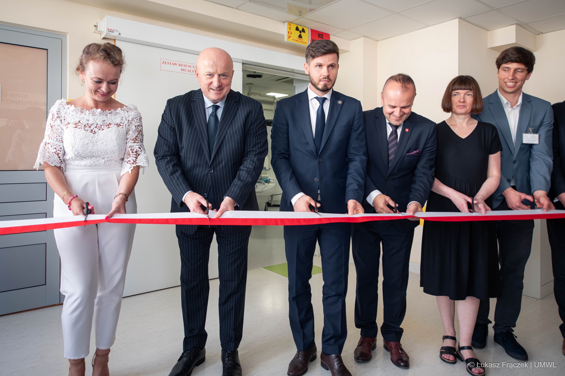Czterech mężczyzn i dwie kobiety podczas przecięcia wstęgi przy otwarciu pracowni tomografii komputerowej