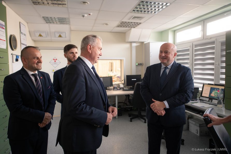 Marszałek Jarosław Stawiarski w towarzystwie dwóch mężczyzn stoi w małym pomieszczeniu