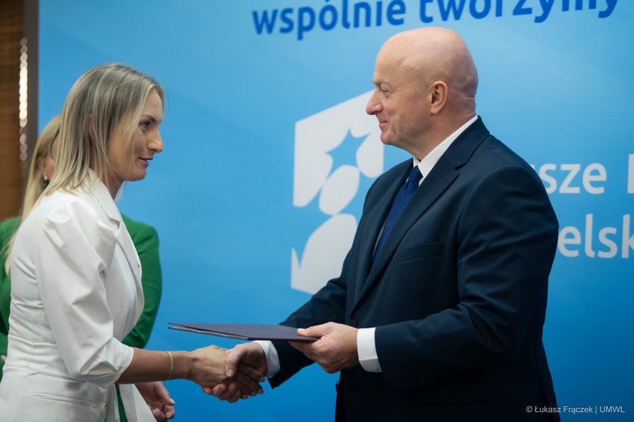 Marszałek Jarosław Stawiarski wręcza kobiecie dokument z dofinansowaniem