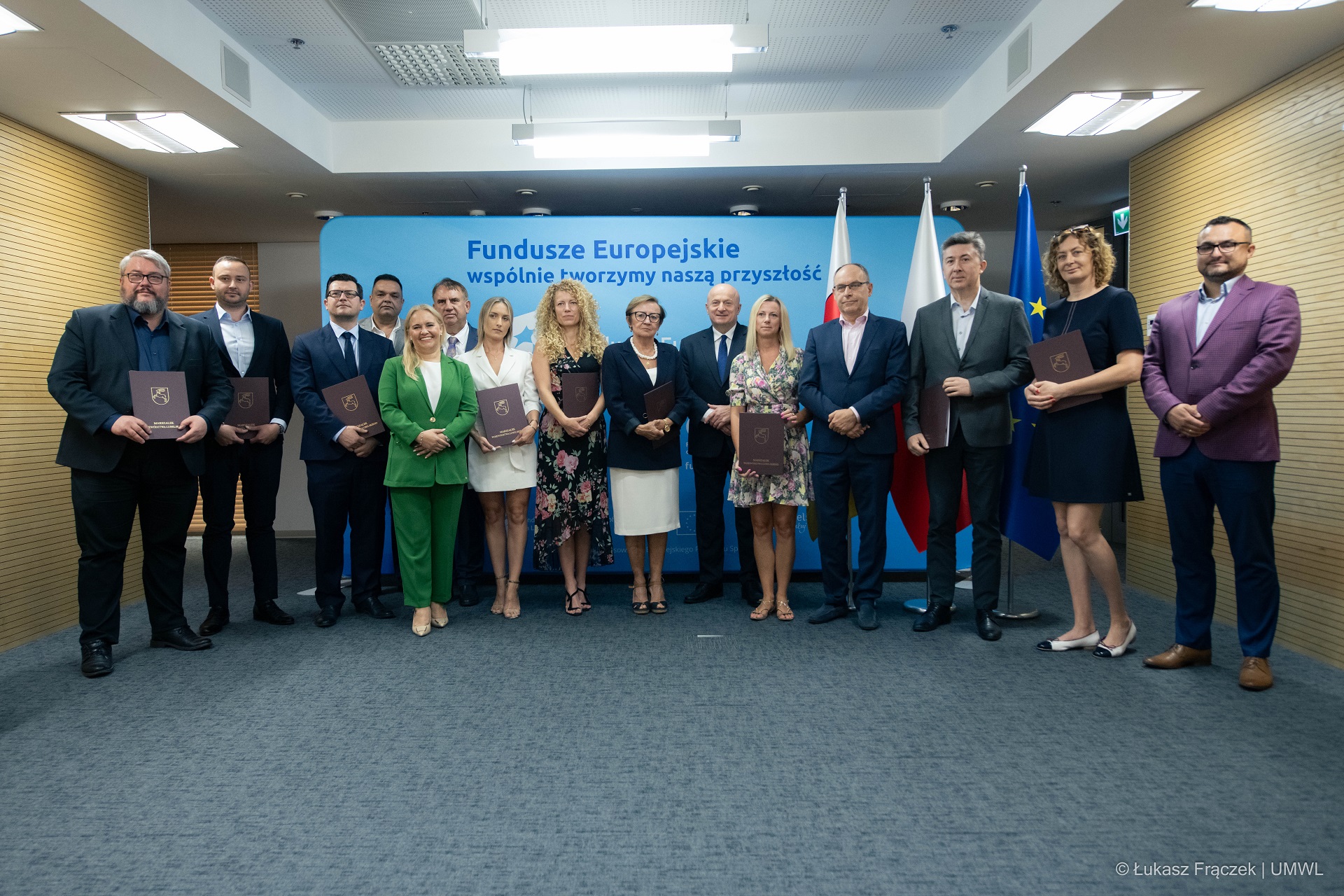 W sali konferencyjnej stoi kilkanaście osób, wszyscy pozują do zdjęcia. Wśród nich stoi marszałek województwa lubelskiego Jarosław Stawiarski