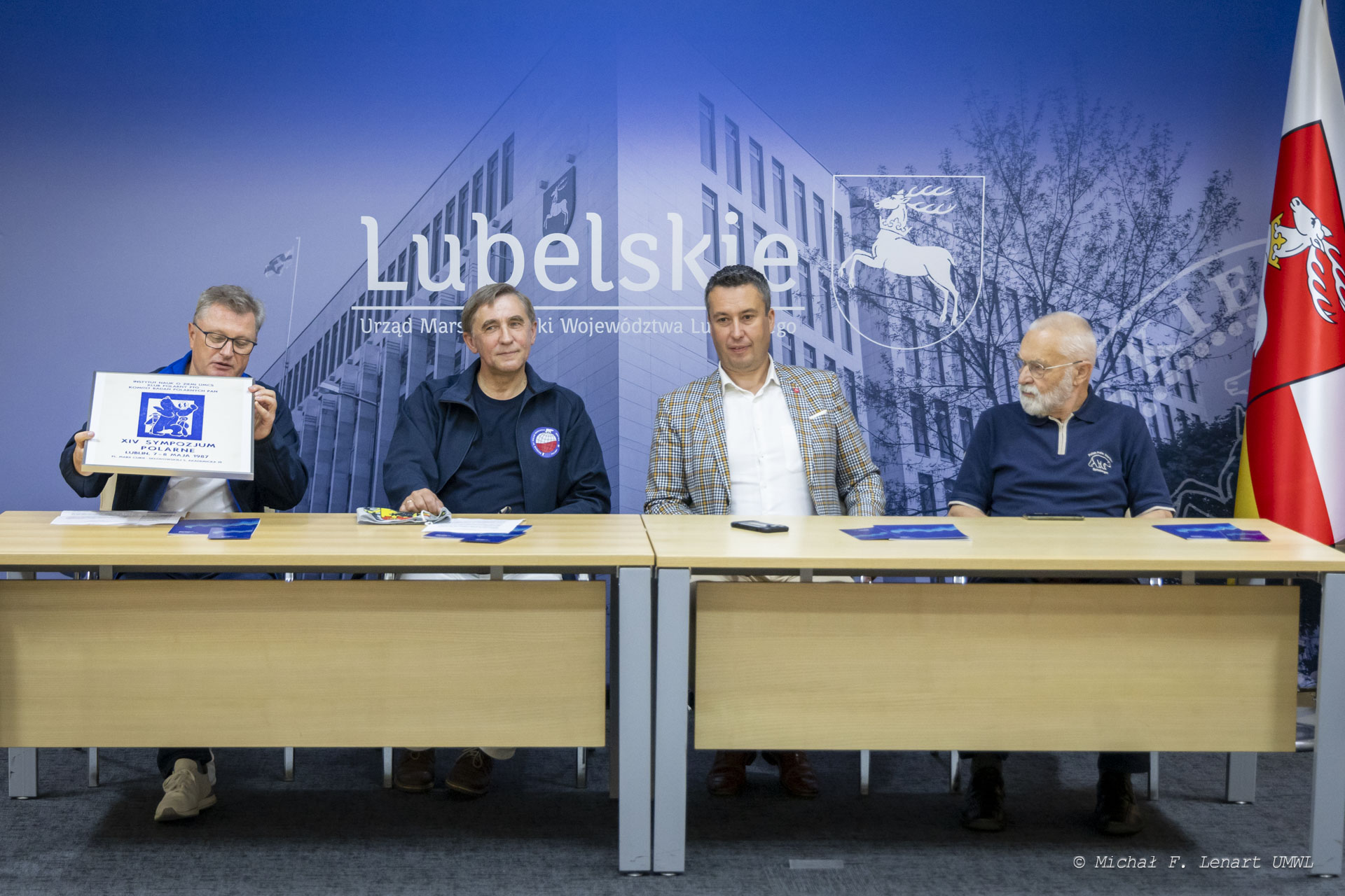 Czterech mężczyzn siedzi przy stole ustawionym w sali konferencyjnej , za nimi znajduje się ścianka z napisem lubelskie