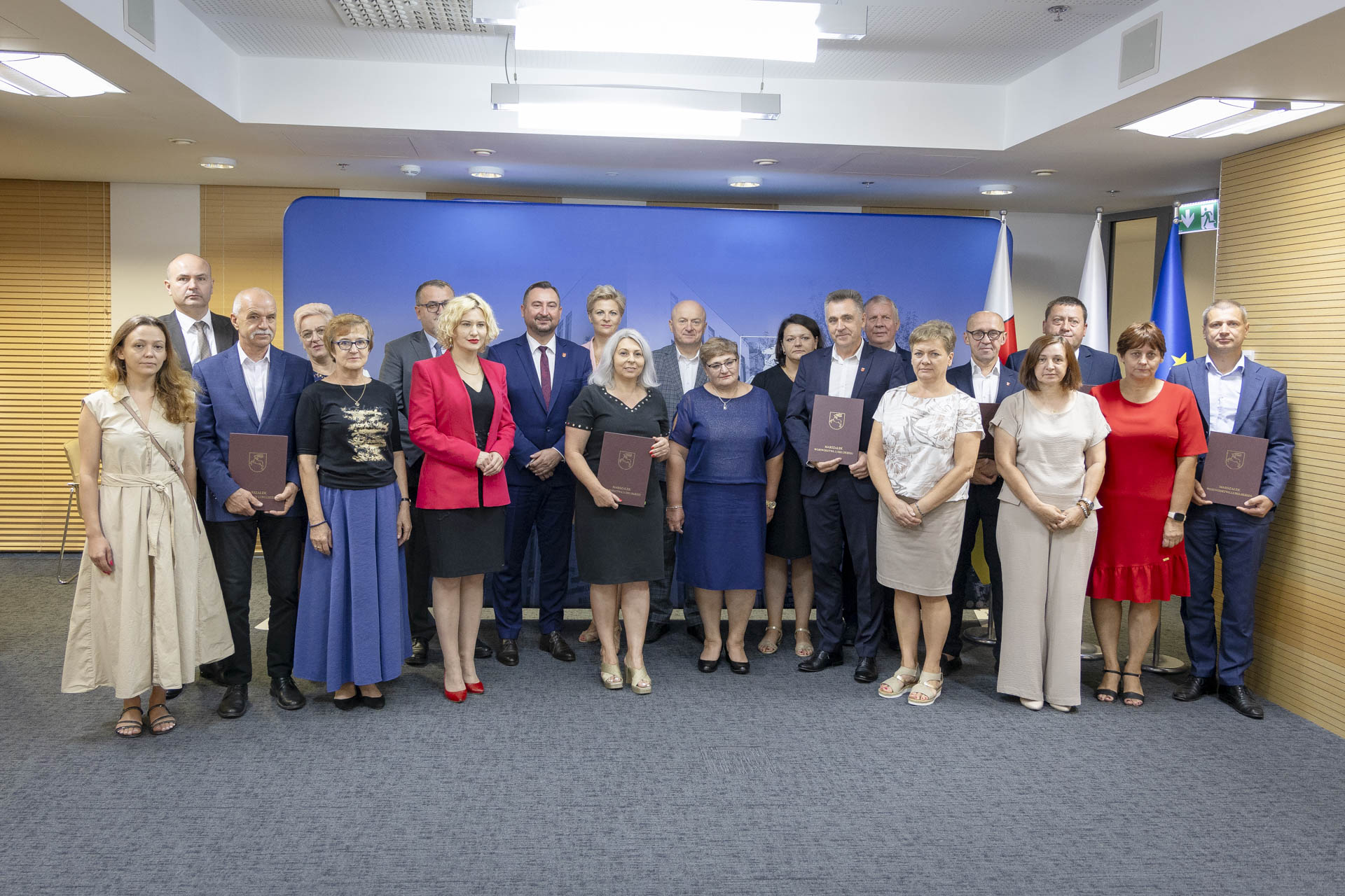 Marszałek i wicemarszałek województwa lubelskiego pozują wspólnie do zdjęcia z około kilkunastoma innymi osobami, które są laureatami dotacji