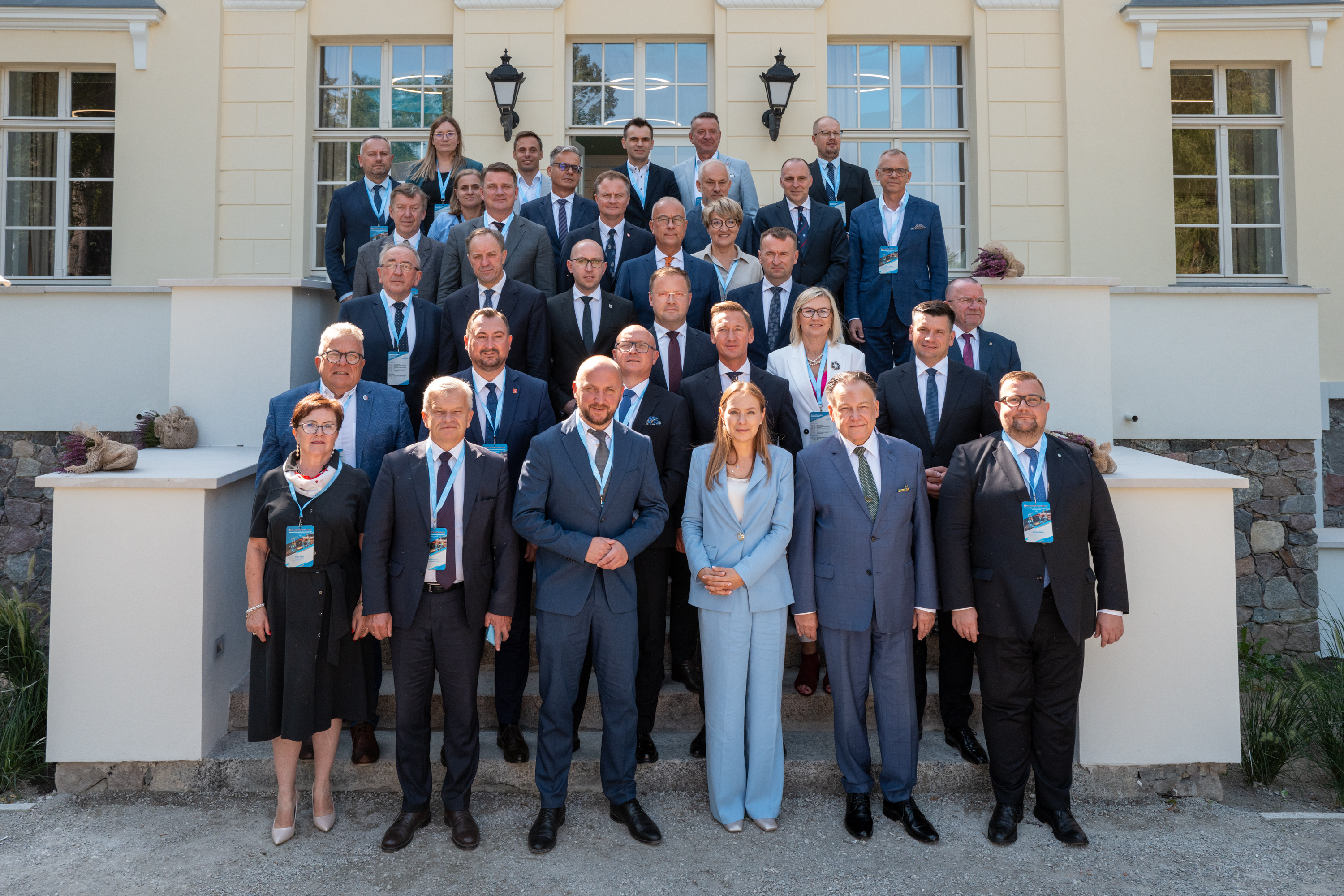 Na zdjęciu widoczna jest grupa ludzi (kobiety i mężczyźni) ustawionych w kilku rzędach. Znajdują się oni na schodach przed wejściem do budynku- pałacu. Są to marszałkowie polskich województw, którzy uczestniczyli w I Posiedzeniu Konwentu Marszałków w Woj. Zachodniopomorskim. Wśród nich (drugi od lewej w drugim rzędzie od dołu) jest Marek Wojciechowski, Wicemarszałek Województwa Lubelskiego