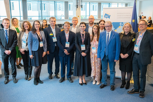 Zespół osób stojący przed banerem, symbolizującym współpracę i wspólne wartości.