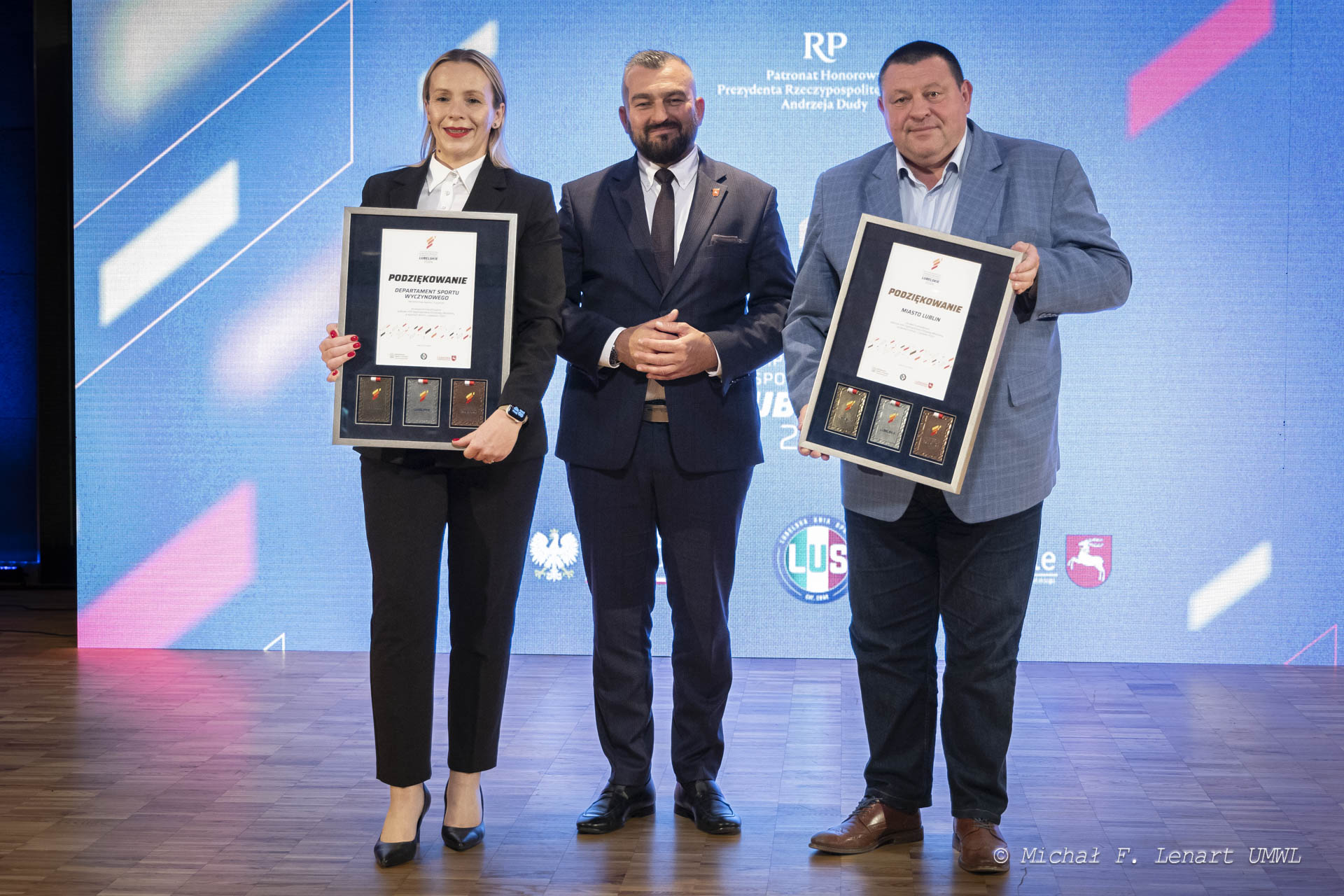 Członek Zarządu Województwa Lubelskiego Jarosław Kwasek w towarzystwie kobiety i mężczyzny którzy trzymają dyplomy oprawione w ramkę