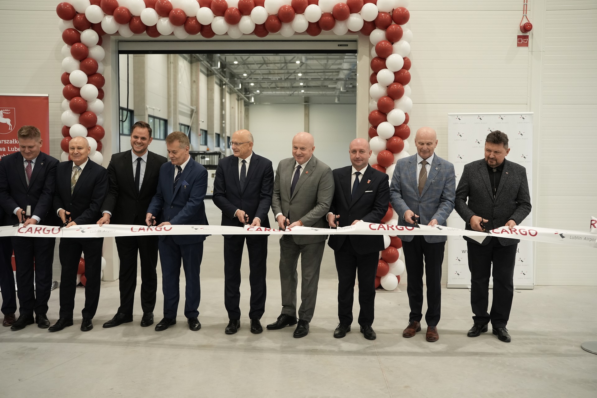 Przedstawiciele władz samorządowych oraz zarzadu lotniska wspólnie przecinają wstęgę podczas otwarcia terminalu