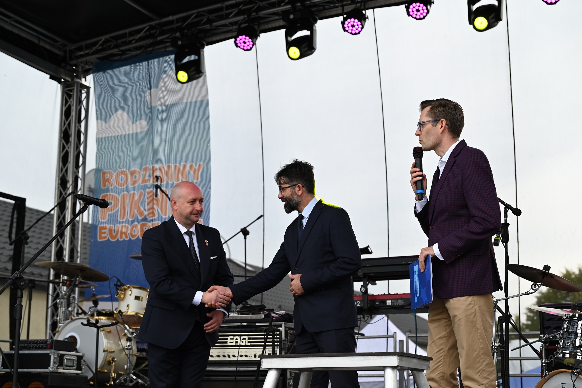 Wicemarszałek Piotr Breś stoi na scenie i podaje rękę konferansjerowi